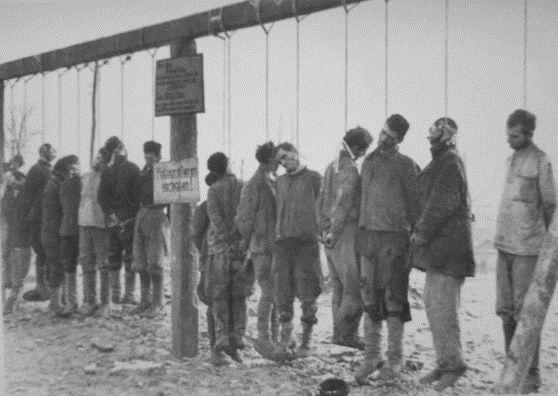 The bodies of hanged Soviet partisans and a sign saying, "No photos!" ("Fotografieren verboten!"). Another sign contains text in German and a Russian translation: "We are bandits; we kill and rob not only German soldiers but also Russian citizens”. https://xn--80aabgieomn8afgsnjq.xn--p1ai/fotografii-poveshennyh-kak-trofei-naczistskie-kazni-sovetskih-zhitelej/